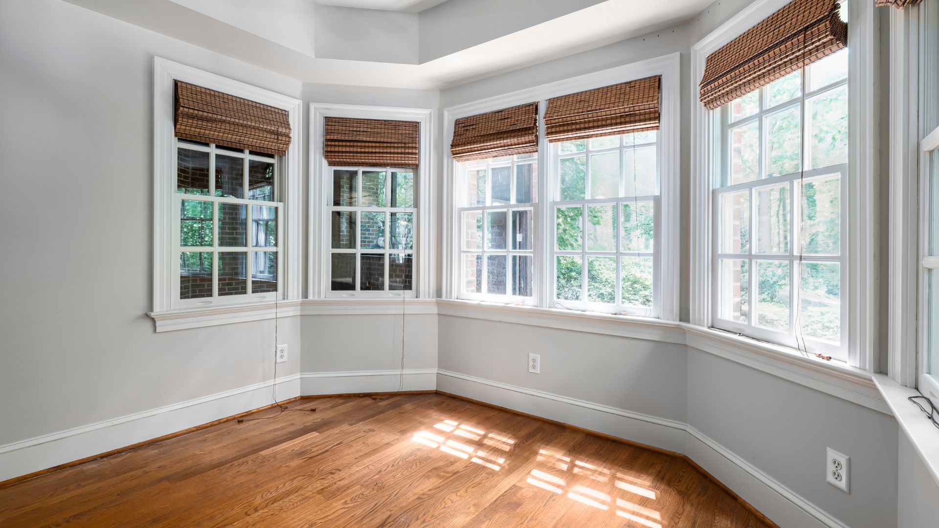 A room featuring four windows that allow natural light to illuminate the hardwood floors.